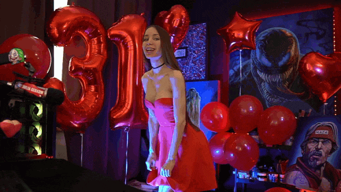 a woman in a red dress stands in front of red balloons and a number 13
