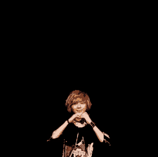 a young man is making a heart shape with his hands in front of a black background .