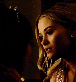 a woman is kissing another woman on the shoulder in a dark room .