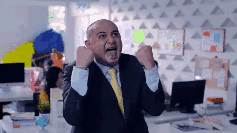 a man in a suit and tie is raising his fists in the air
