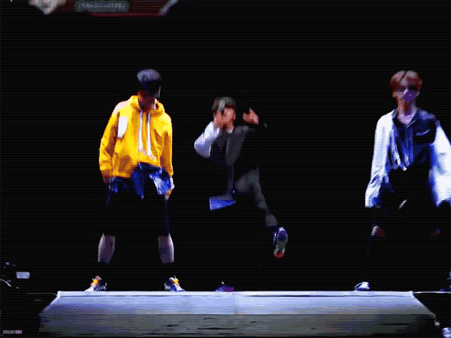a man is singing into a microphone while dancing on a stage in a dark room .