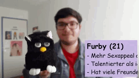 a man is holding a furby stuffed animal in his hand