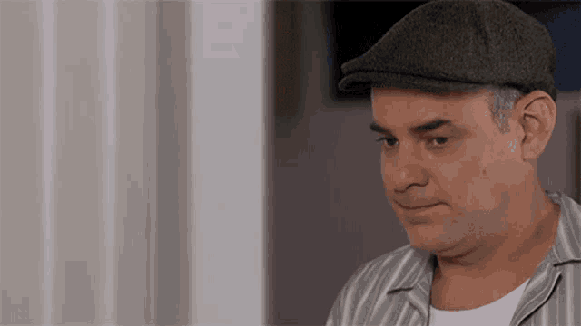 a man wearing a flat cap and a striped shirt is smiling