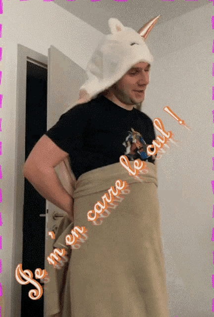a man wearing a unicorn hat is wrapped in a blanket with the words je m en carre le cul