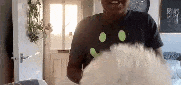 a woman is standing in a living room with a stuffed animal in her hand .