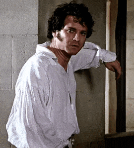 a man in a white shirt is leaning against a wall and looking out of a window .