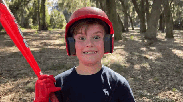 a young boy wearing a helmet and headphones is holding a baseball bat