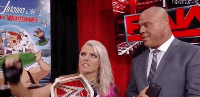 a man in a suit and tie is standing next to a woman in a wrestling ring .