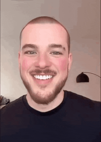 a man with a beard and a mustache is smiling with his mouth open .