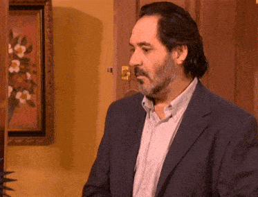 a man with a beard is standing in front of a painting