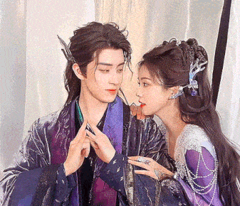 a woman in a purple dress is licking a man 's nose