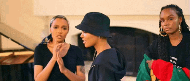 a woman wearing a black hat and a black shirt with the word peace on it stands next to two other women