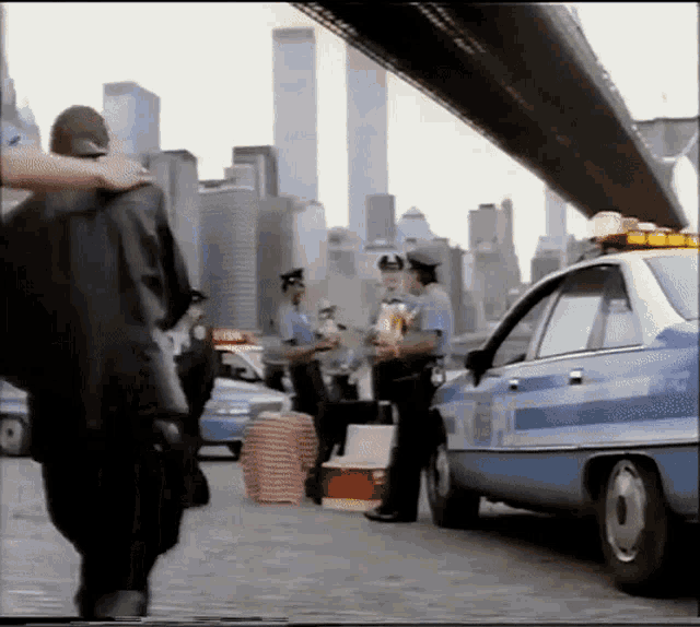 a group of police officers are standing in front of a blue police car