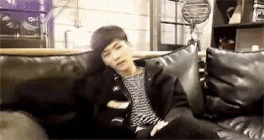 a young man is sitting on a couch in a living room .