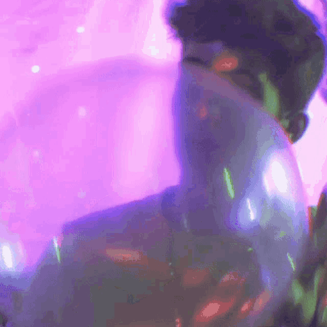 a man is covering his face with a purple and green light