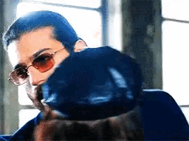 a man wearing sunglasses and a blue jacket is looking at a woman .