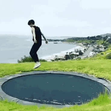 a person is jumping on a trampoline in front of a beach