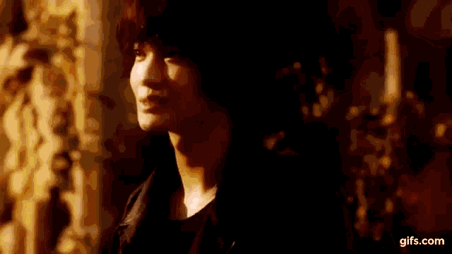 a close up of a person 's face in a dark room with candles in the background .