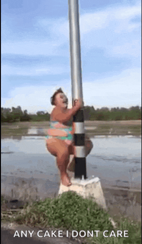 a woman in a bikini is hanging from a pole in the water .