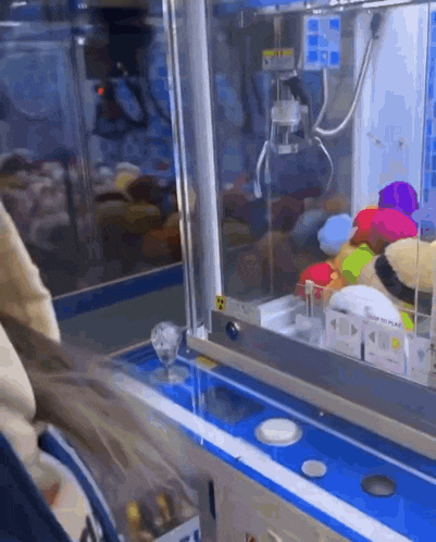 a person is playing a game with a machine that says ' claw machine ' on it .