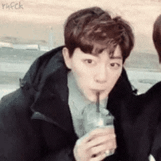 a young man is drinking a beverage through a straw .