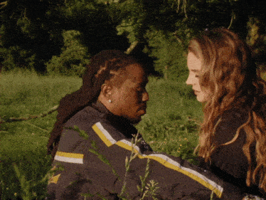 a man and a woman are looking into each other 's eyes in a field