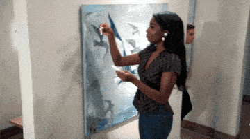a woman is painting a picture of birds on a canvas