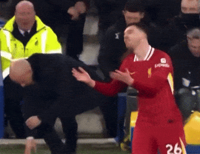 a soccer player in a red jersey with the number 26 on it is being helped by a man .