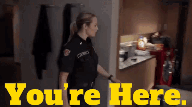 a police officer is standing in a kitchen with the words you 're here