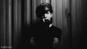 a blurry picture of a man standing in front of a curtain .