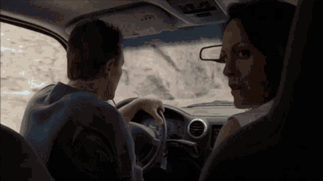 a man and a woman are sitting in a car