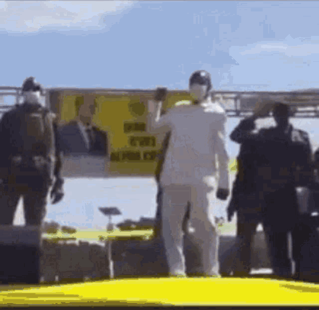 a man in a white suit is standing in front of a yellow sign that says ' freedom ' on it .