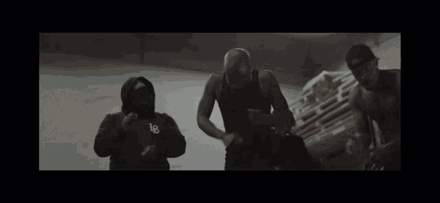 a man in a hoodie with the letter b on it is standing next to two other men