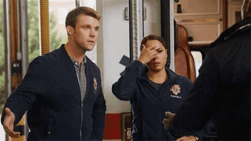 a man and a woman are standing in front of an ambulance and talking to each other .