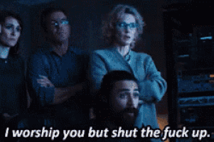 a group of people standing in front of a screen with a caption that says i worship you but shut the fuck up