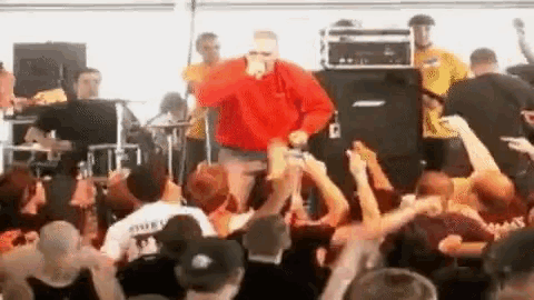 a man in a red sweatshirt is standing in front of a crowd of people .