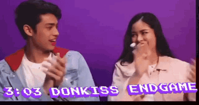 a man and a woman are clapping in front of a purple background that says 3:03 donkiss endgame on it