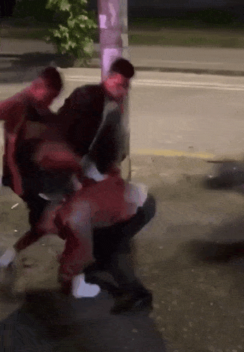 a man in a red jacket is being attacked by another man