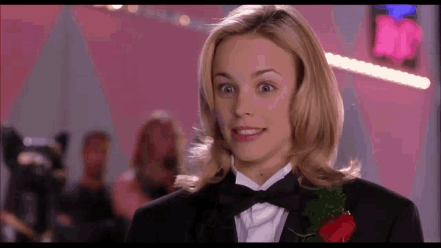 a woman wearing a tuxedo with a red rose in her lapel