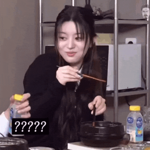 a woman is eating food with chopsticks and a bottle of water .