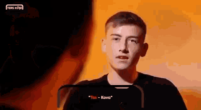 a young man in a black shirt is talking to another young man in a dark room .
