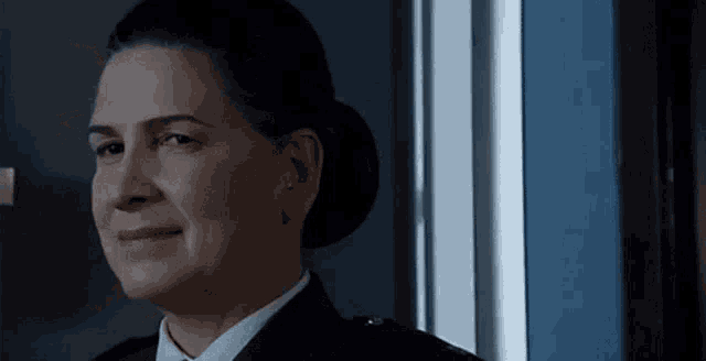 a woman in a police uniform is smiling while looking out of a window .