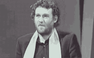 a man with a beard is wearing a scarf around his neck and a suit .
