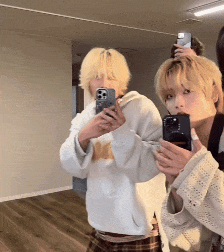 two people are taking a picture of themselves in a mirror with their phones