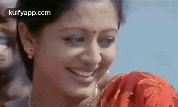 a woman is smiling and looking at the camera while wearing a red shirt .