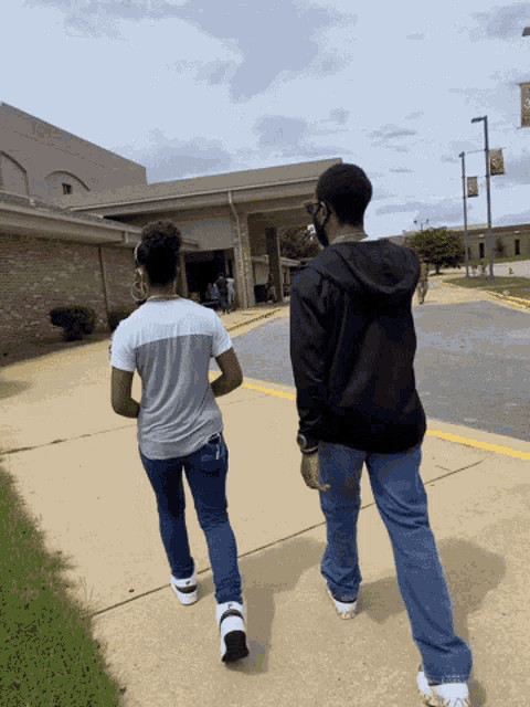 a man and a woman walking down a sidewalk in front of a building