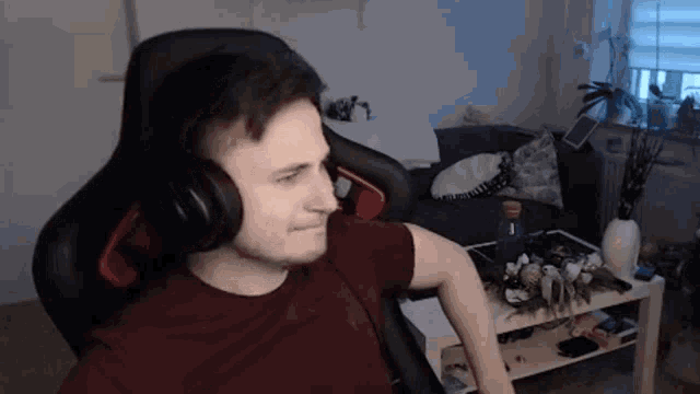 a man is wearing headphones while sitting in a chair in a living room .