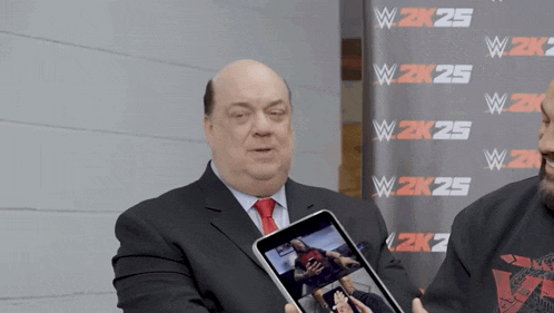a man in a suit and tie is holding a tablet in front of a wall that says w 2k25