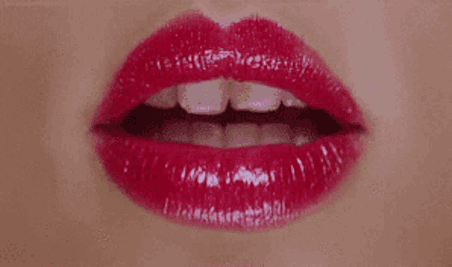 a close up of a woman 's lips with red lipstick and white teeth .