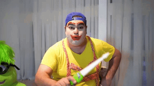 a man in a clown costume is holding a green squirt gun
